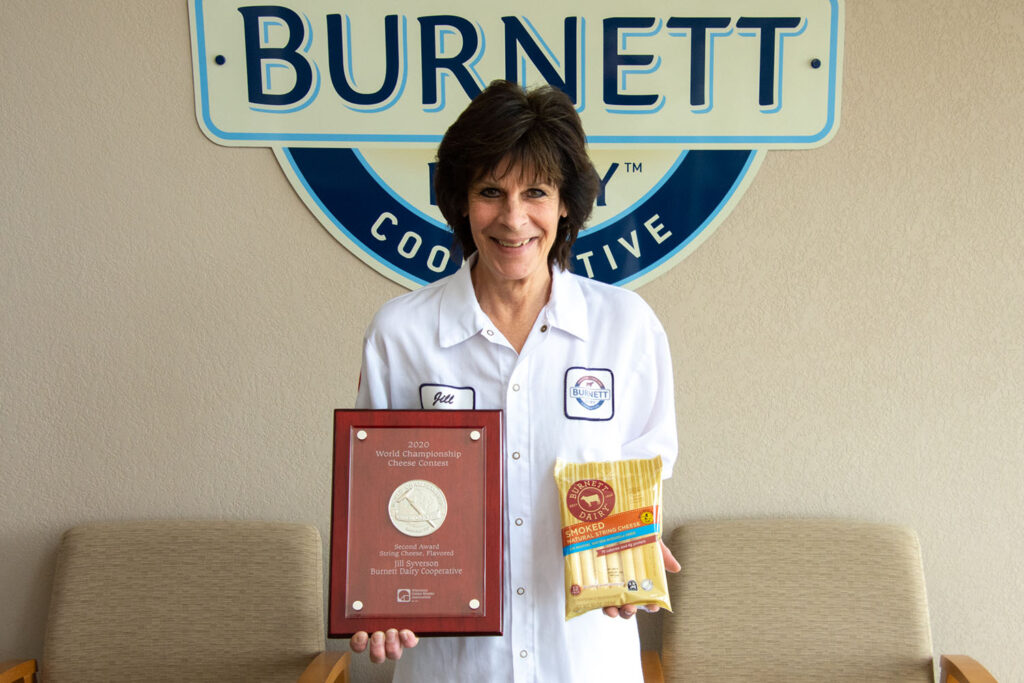 Jill-Syverson is the World Champion in the Cheese Contest of 2020-2; Jill is pictured holding her winning packaged cheese and award placard.